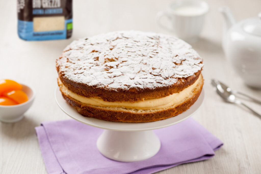 Torta Bienenstich fatta in casa con pesche, crema pasticcera e lo zucchero di canna biologico grezzo di Italia Zuccheri